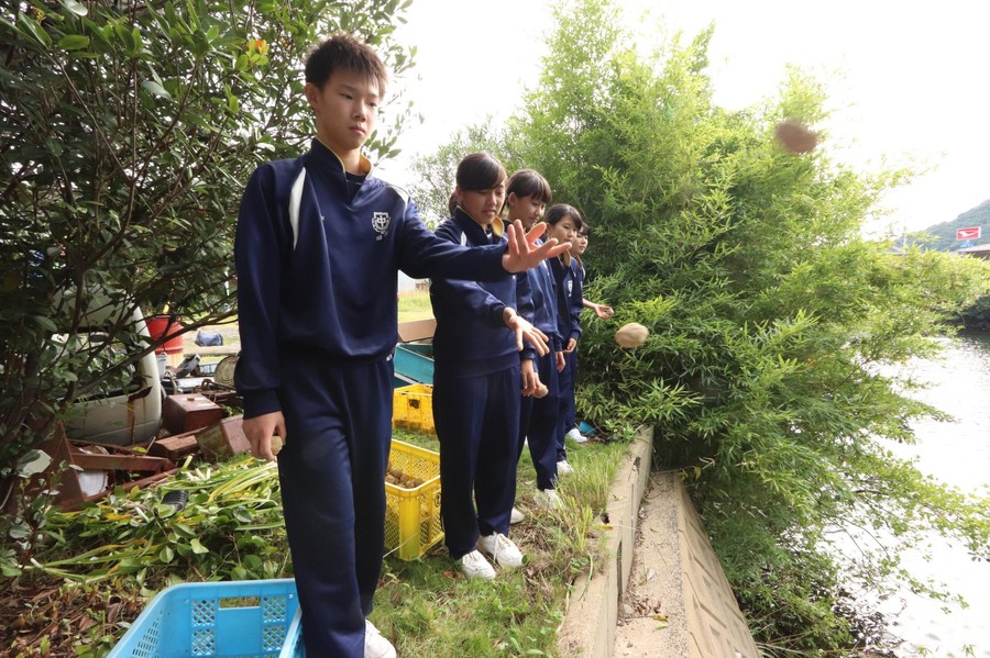 长崎环境美化团体与当地中小学生将净水丸投入池中