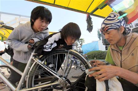 志愿者用废墟中发现的零部件为灾区人民修理自行车